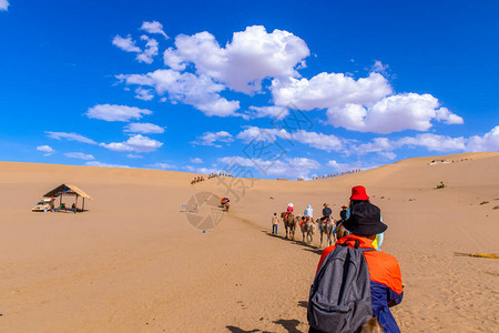 一群游客乘骆驼前往甘肃市邓华丝绸之路的沙山MingshaShan沙漠或歌唱沙丘和大篷车Lilk背景图片