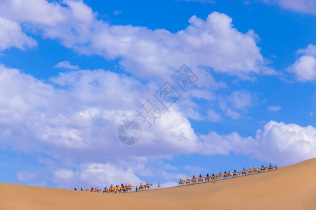 一群游客乘骆驼前往甘肃市邓华丝绸之路的沙山MingshaShan沙漠或歌唱沙丘和大篷车Lilk图片