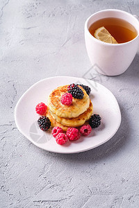 小屋奶酪煎饼凝乳油条甜点覆盆子和黑莓浆果放在盘子里图片