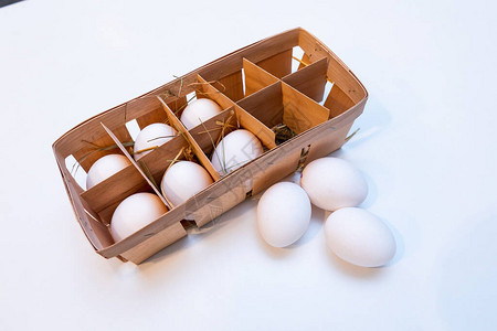 白色背景上干草中木箱里的鸡蛋图片