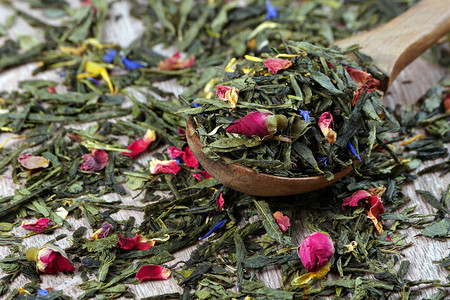 木桌上的绿茶干玫瑰花和香料图片