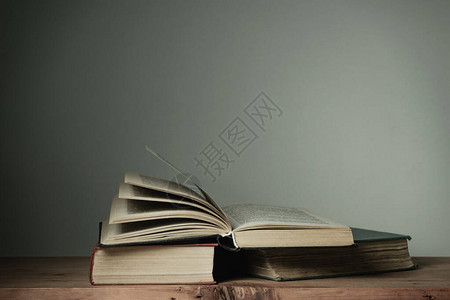 旧红木桌和白墙背景上的漂亮打开书籍背景图片