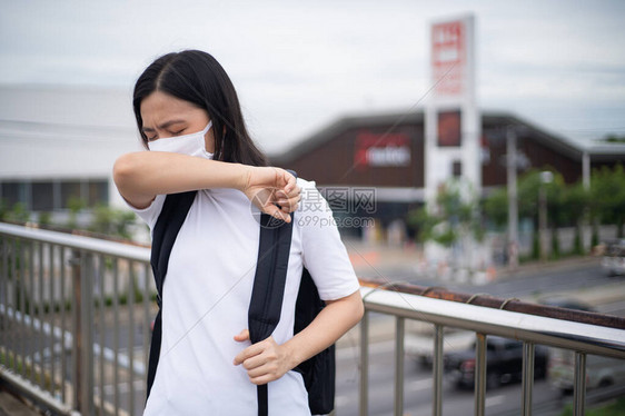 身着防护面罩戴防毒和污染面具咳嗽和站在横越城市街道的亚洲妇女图片