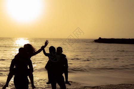 日落时在海上附近人们的轮廓年轻人暑假过得很愉快旅行聚会和友背景图片