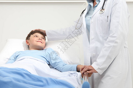 快乐的孩子躺在病房的床上医生安慰他图片