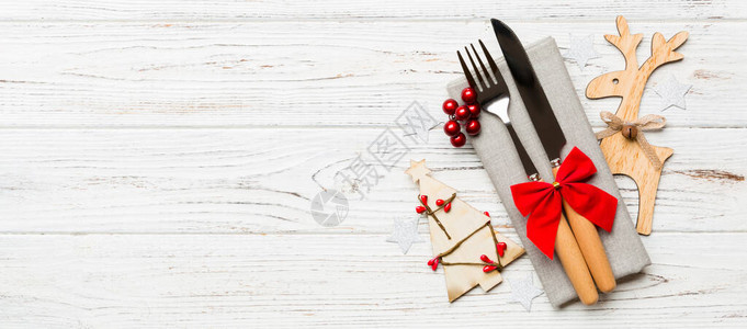 新年横幅套装餐巾纸上的叉子和刀子木制背景上的圣诞装饰品和驯鹿的顶部视图假日家庭晚餐概念背景图片