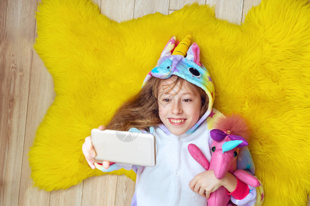穿着独角兽睡衣的可爱女孩带着玩具自拍图片