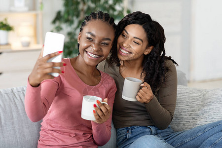 欢乐的非洲情妇在家里喝茶时图片