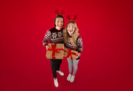 幸福的一对夫妇穿着羊毛衫和鹿角圣诞礼物图片