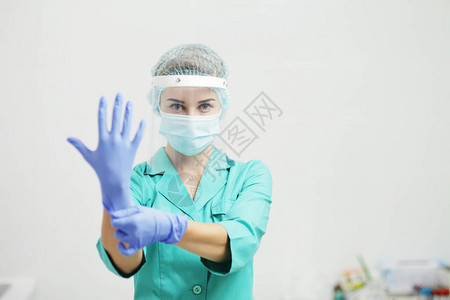 穿着制服医用口罩面罩的女医生或护士戴上手套冠状COVID19图片