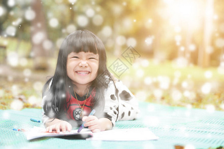 亚洲儿童或女孩在秋季花园的绿色垫子和自然草地上学习着色或睡眠绘画图片