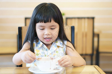 亚洲儿童可爱或小女孩微笑着洁白的牙齿和美味的热可或牛奶巧克力饮料图片