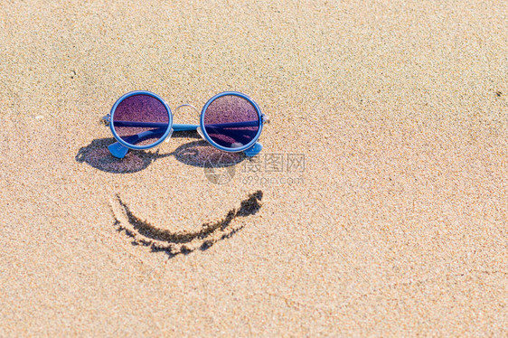 太阳镜和沙滩上的彩绘微笑旅游理念图片