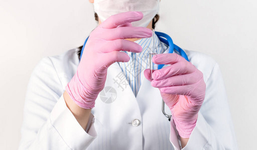 白大衣医疗面具和带薄膜疫苗的粉色消毒手套中年轻女医生的切片视图图片