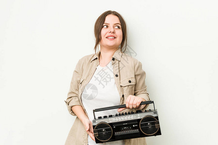 年轻卷发女人拿着复古收音机看着微笑欢乐图片