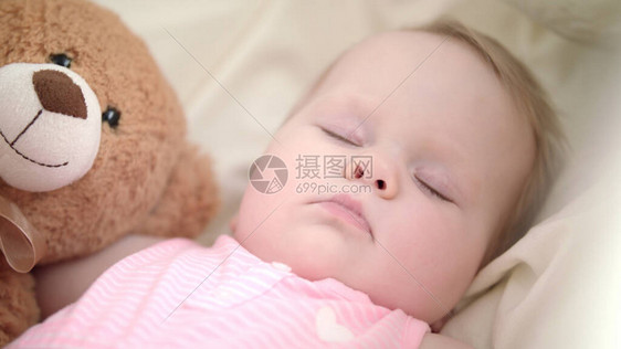 可爱的宝睡在床上关闭与玩具睡觉的女婴儿床里可爱的孩子脸幼儿的梦想时间孩子们的摇篮曲睡前概念睡着图片