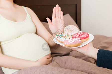 住在床上的近身孕妇拒绝吃甜圈等垃圾食品图片