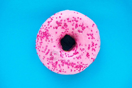 蓝色背景上的甜粉色甜圈甜面团产品图片