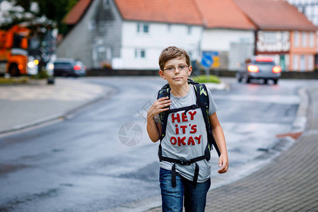 戴着眼镜和背包或书包的快乐小男孩在去初中或高中的路上的小学生雨天在街上户外健康可爱的孩图片