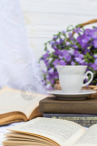 柳条篮中的杯咖啡茶书籍和亚麻花束图片