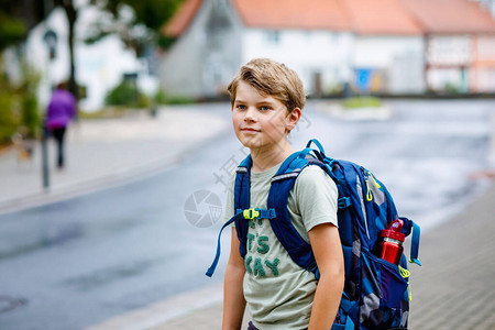 快乐的小男孩背着包或书包在去初中或高中的路上的小学生雨天在街上户外健康可爱的孩图片