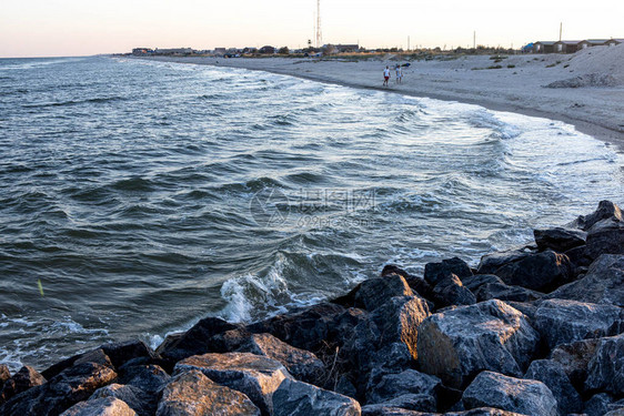 石头和沙子海滩在夕阳的光芒中挥舞着海浪图片