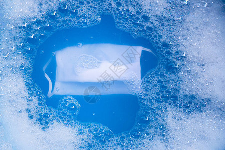 清洗前浸泡在粉末清洁剂水溶解中的白布面罩图片