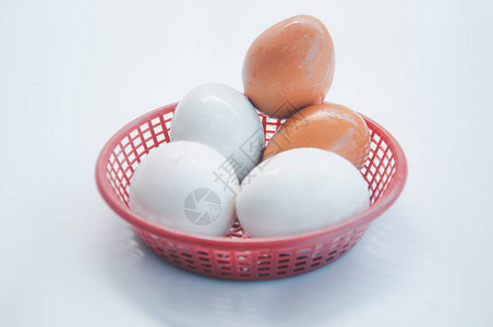 三个咸蛋和两个鸡蛋在白色背景的红色篮子里图片