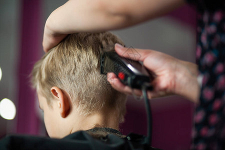 一个可爱的小男孩坐在造型师的理发店里图片