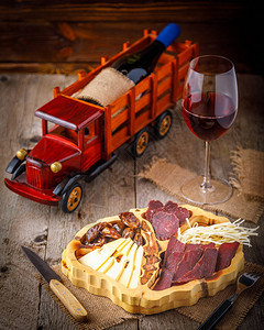 木板上的变种肉和奶酪和一杯红酒图片