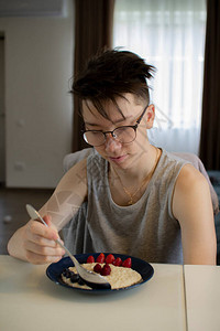 一个十几岁的孩子吃燕麦粥和浆果图片