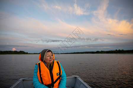 日落时船上穿着橙色背心的女人图片