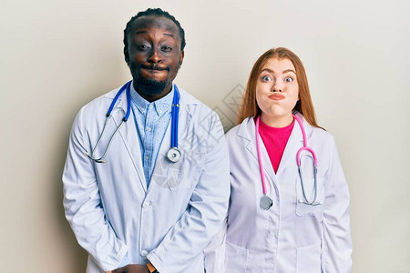 穿着医生制服和听诊器的年轻异族夫妇用笑脸抽图片