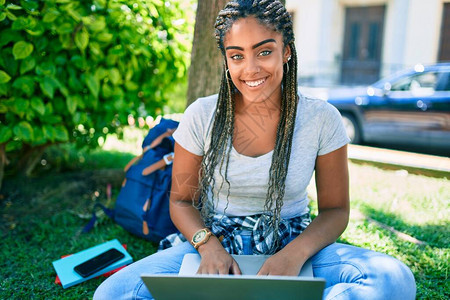 年轻非洲女学生在大学校园的草地上用电脑笔记本电脑坐在草地上图片