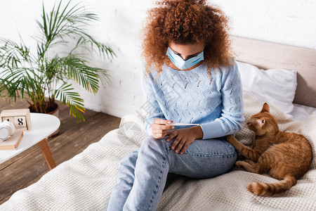 身戴医疗面罩坐在床上猫附近时戴着温度图片