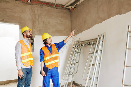 粗鲁的建筑工人显示正在建造的建筑房屋顶图片