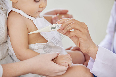 儿科医生用电子温度计检查小女婴体图片