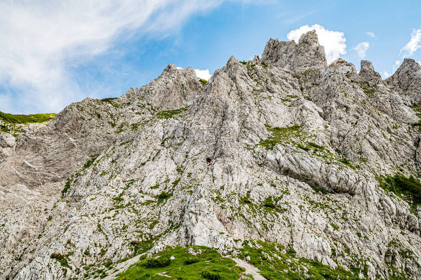 年轻女子夏季徒步旅行者背着包在金属电缆铁梯级钉子和通过铁索攀爬巨大石灰岩壁的帮助下攀爬斯洛文尼亚卡拉万克山脉和卡林西亚卡拉万肯山图片