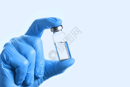 蓝色手套把药瓶和疫苗或药物放在蓝底图片