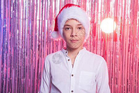 圣诞节的时候有圣诞老人帽子的十几岁的男孩在闪亮的节日背图片