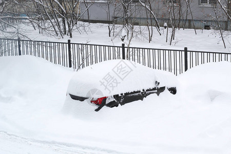 这辆车几乎完全被雪覆盖在围栏前面的院子图片