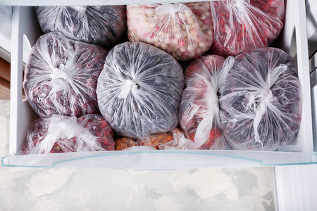 在冰箱的透明塑料袋中冷冻浆果打开装满冷冻浆果和水果的冰箱素食图片
