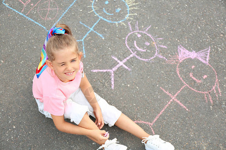 小女孩用粉笔在沥青上画图片