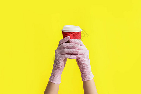 手戴保护手套用彩色背景咖啡杯图片