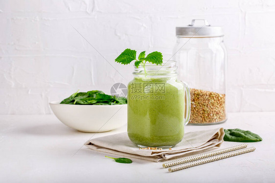 在白色的玻璃罐子里喝绿色冰淇淋混合鸡尾酒加菠菜和绿图片