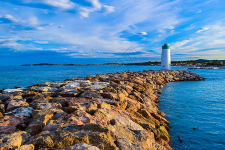 灯塔位于保护码头入口的断流水岩石上背景图片