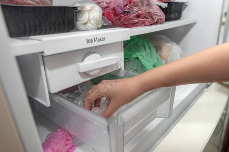 女孩从冰箱的制冰机里取冰块来冷却饮料图片