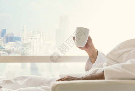 清晨放轻松概念一个年轻人在窗前喝咖啡放松时的侧面景象与早晨阳光相伴图片