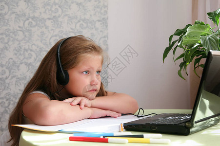 悲伤的孩子在家里戴着耳机戴着耳机在家里使用笔记本电脑图片