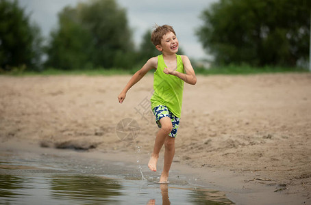 快乐的男孩沿着海滩奔跑一个孩图片